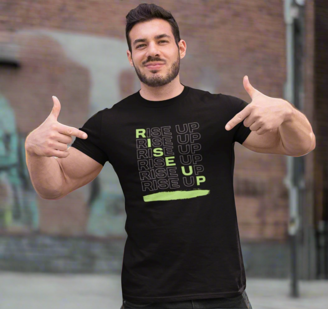 Man wearing a black t-shirt with 'RISE UP' text, posing in front of a graffiti-covered wall.